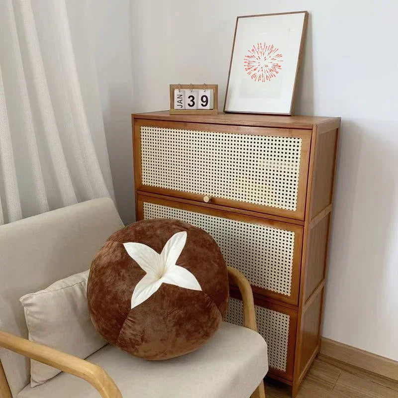Minimalist living space with rattan cabinet, cozy armchair, and round brown throw pillow