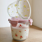 Glass food containers with floral print and pink lids on wooden table