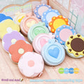 Colorful macaron-shaped measuring tapes in floral and heart designs on wooden surface